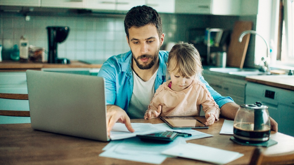 Young father embracing his daughter while working with documents