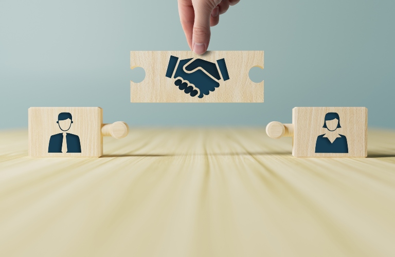 wooden blocks with icons of a woman and a man and shaking hands in the act of conserns