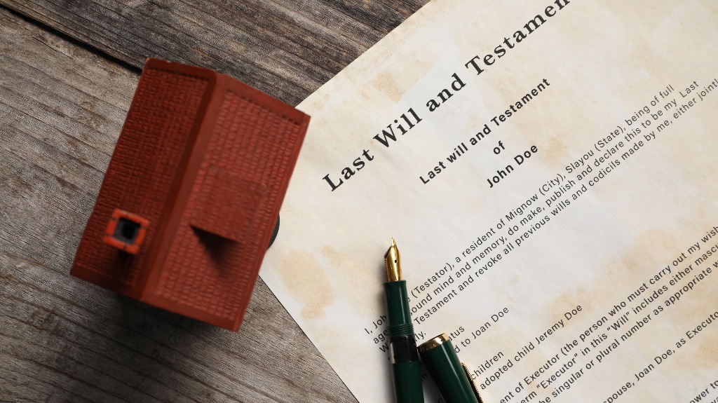 Last Will and Testament with fountain pen and house model on wooden table