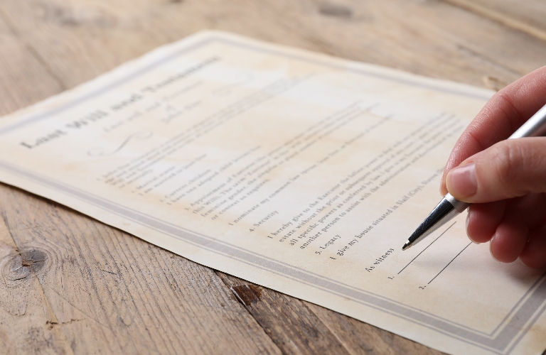 Woman signing Last Will and Testament at wooden table