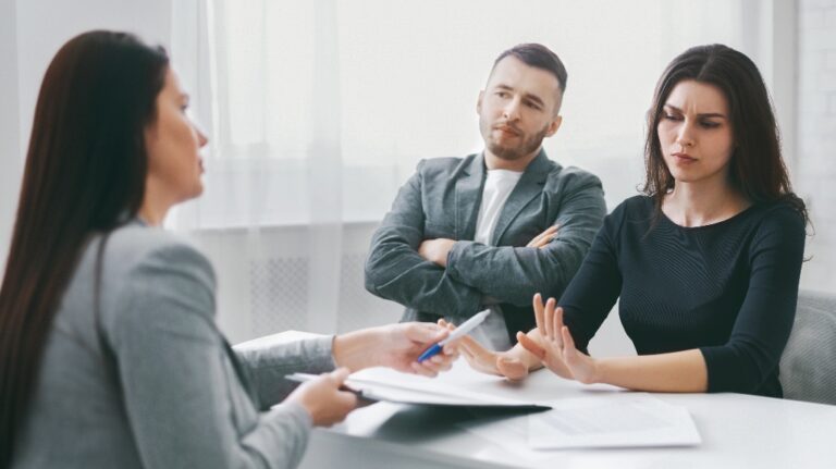 couple is sitting at a table in an office and meeting with a lawyer