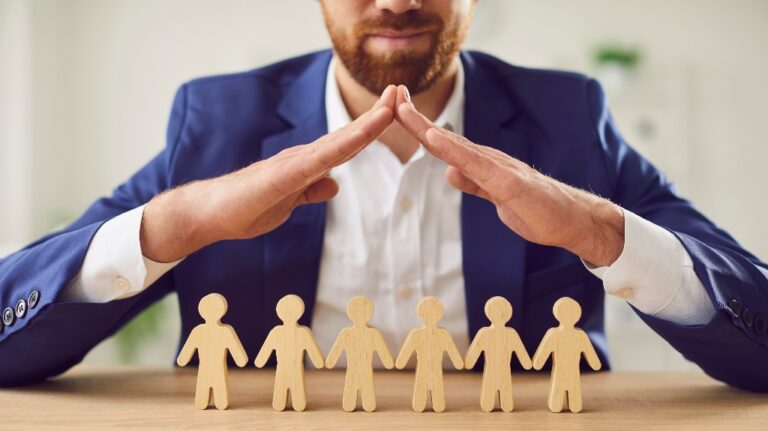Man hands above small wooden toy human figures