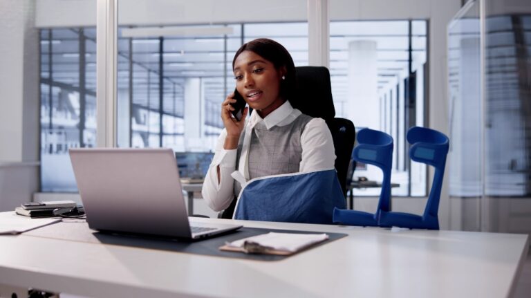 A woman with Injured hand sittig in the office and talking to the phone