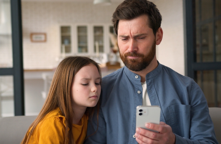 father and daughter look at phone